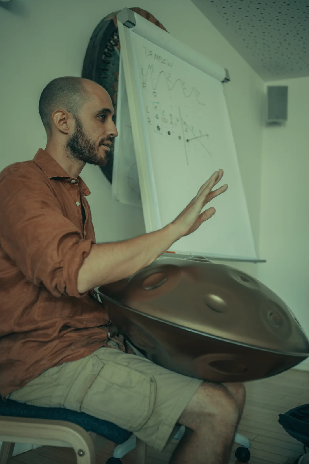 Amarok explaining handpan theory with a diagram behind him