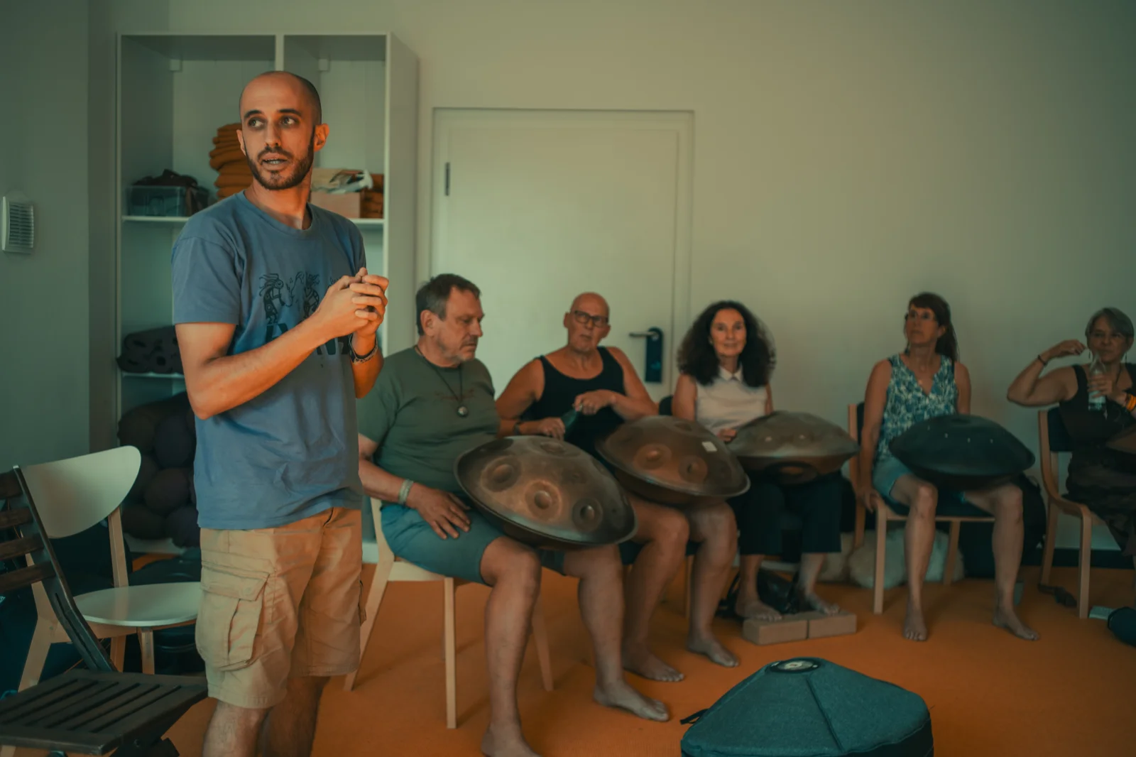 Amarok standing and teaching a circle of students holding handpans
