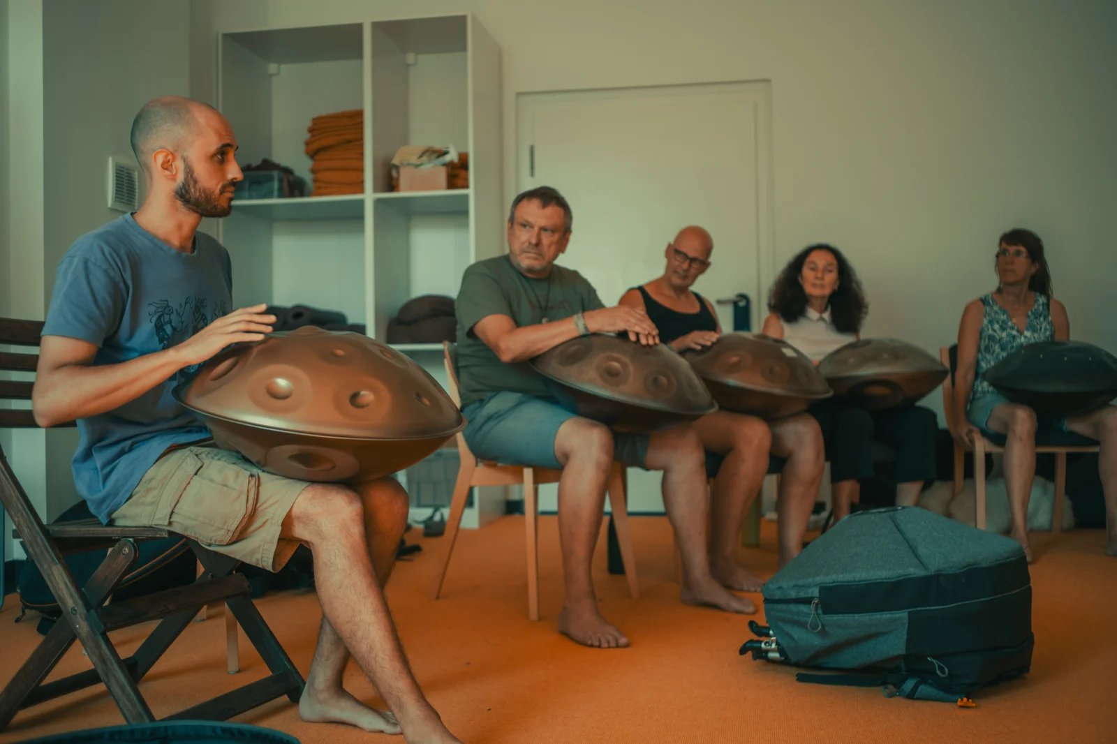 Amarok seated in a circle of students playing handpans together